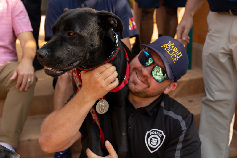 Police officer with arm around dog