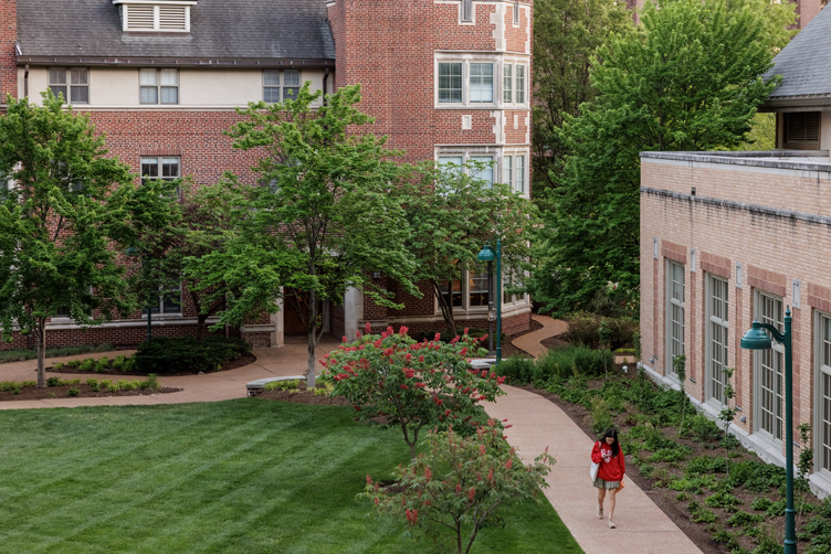 Student walking in the exterior Residential Life common spaces on the South 40